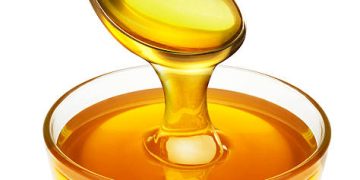 honey pouring from spoon into the bowl