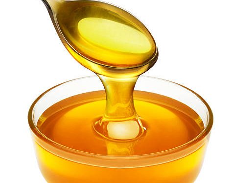 honey pouring from spoon into the bowl