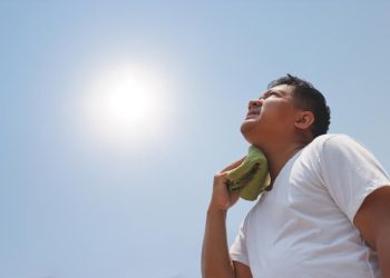 man in the sun holding wet cloth to neck